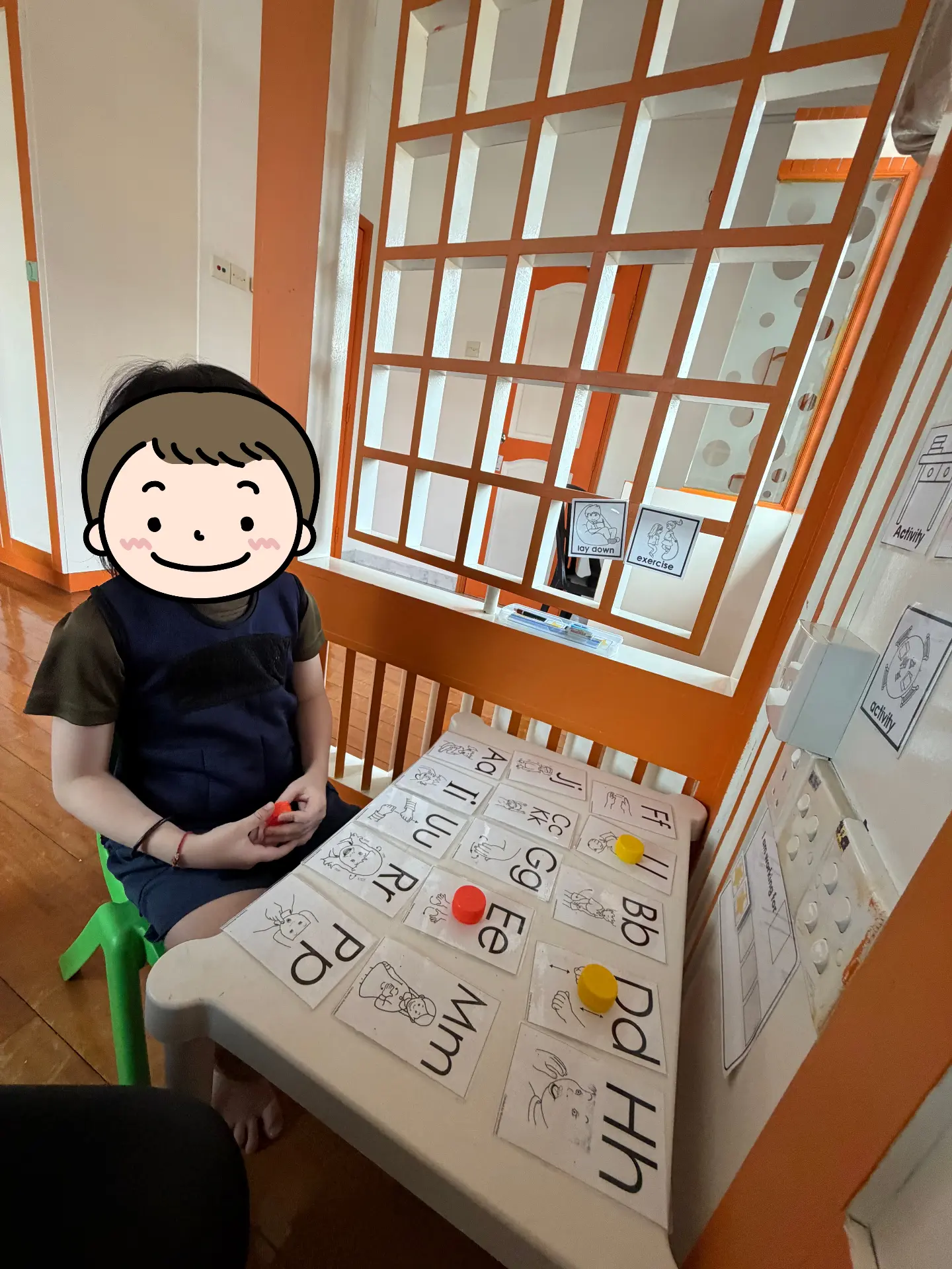 A child sitting at a table with letter cards and activity sheets.