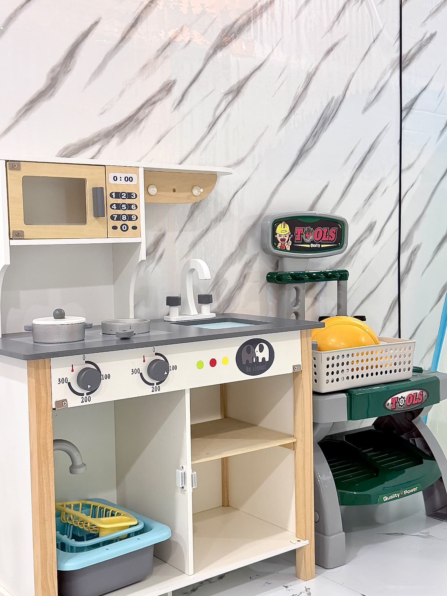 A wooden play kitchen and toy workbench set up for pretend play.