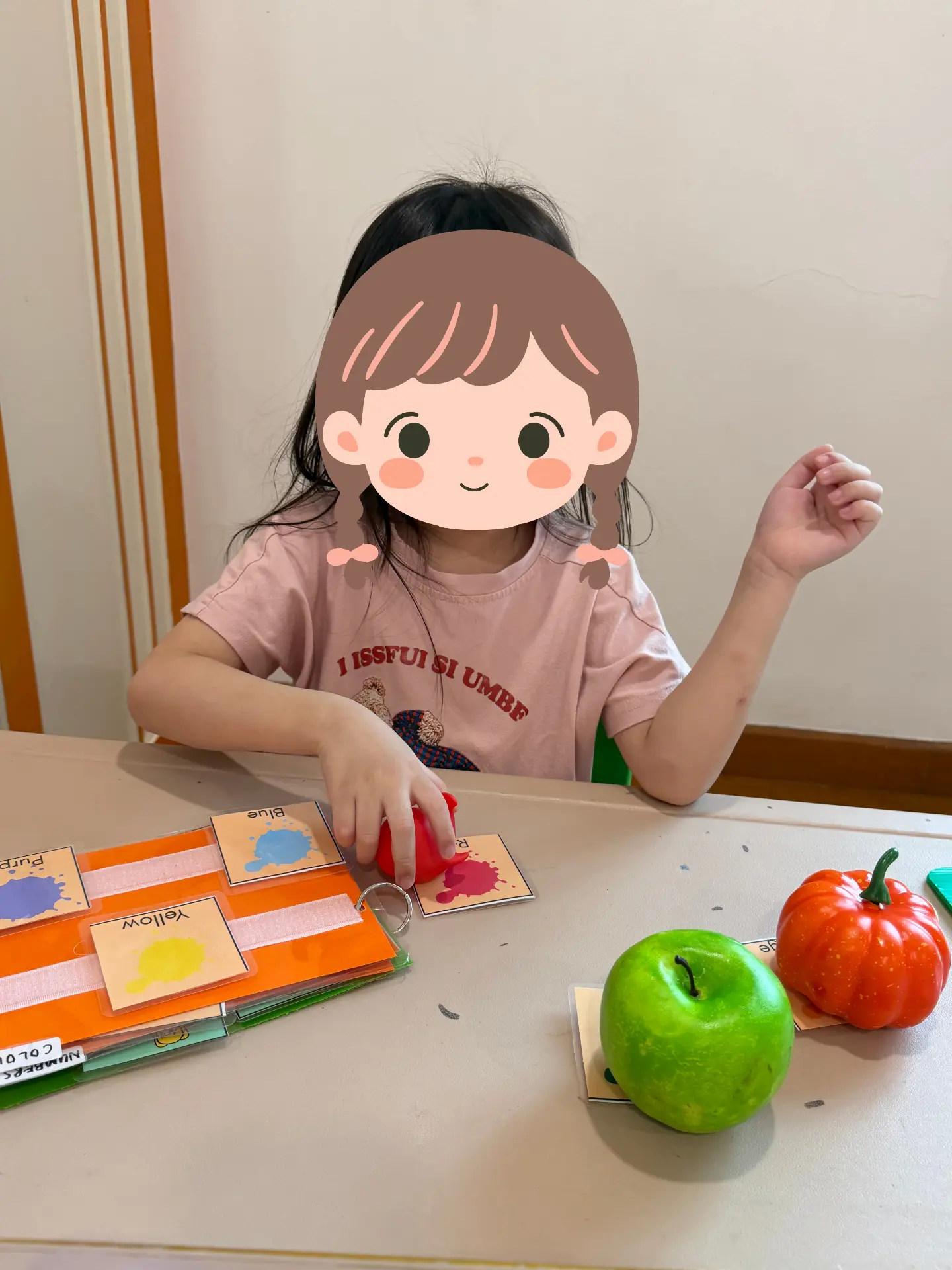 A child matching coloured apples to colour cards at a table.