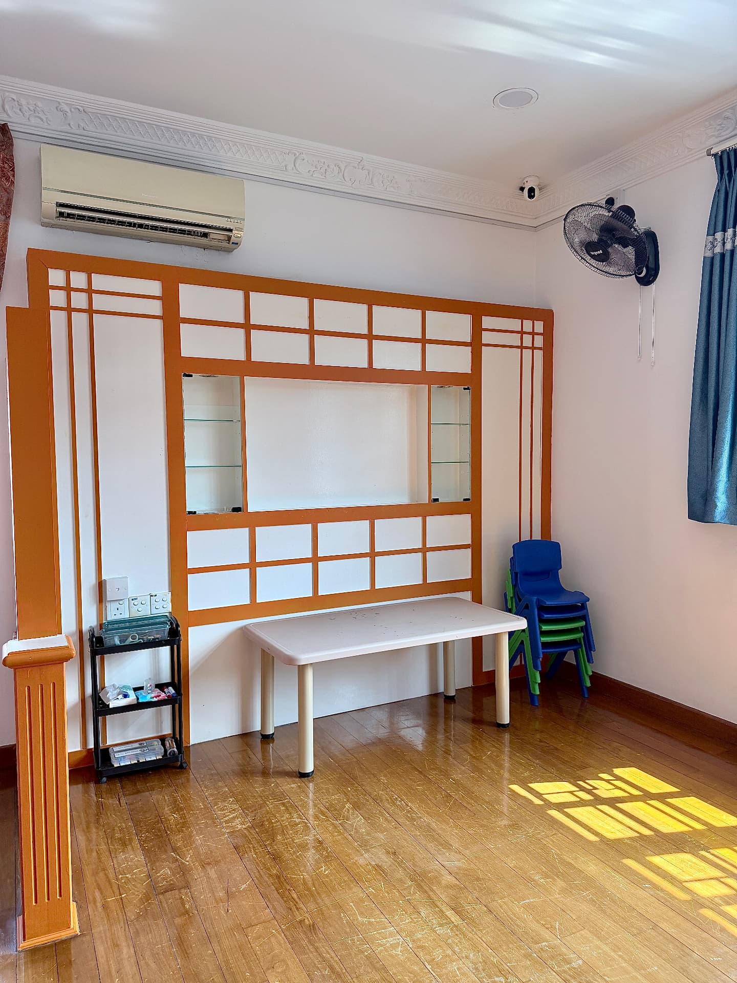 A spacious room with a wooden partition, table, and stacked colourful chairs.