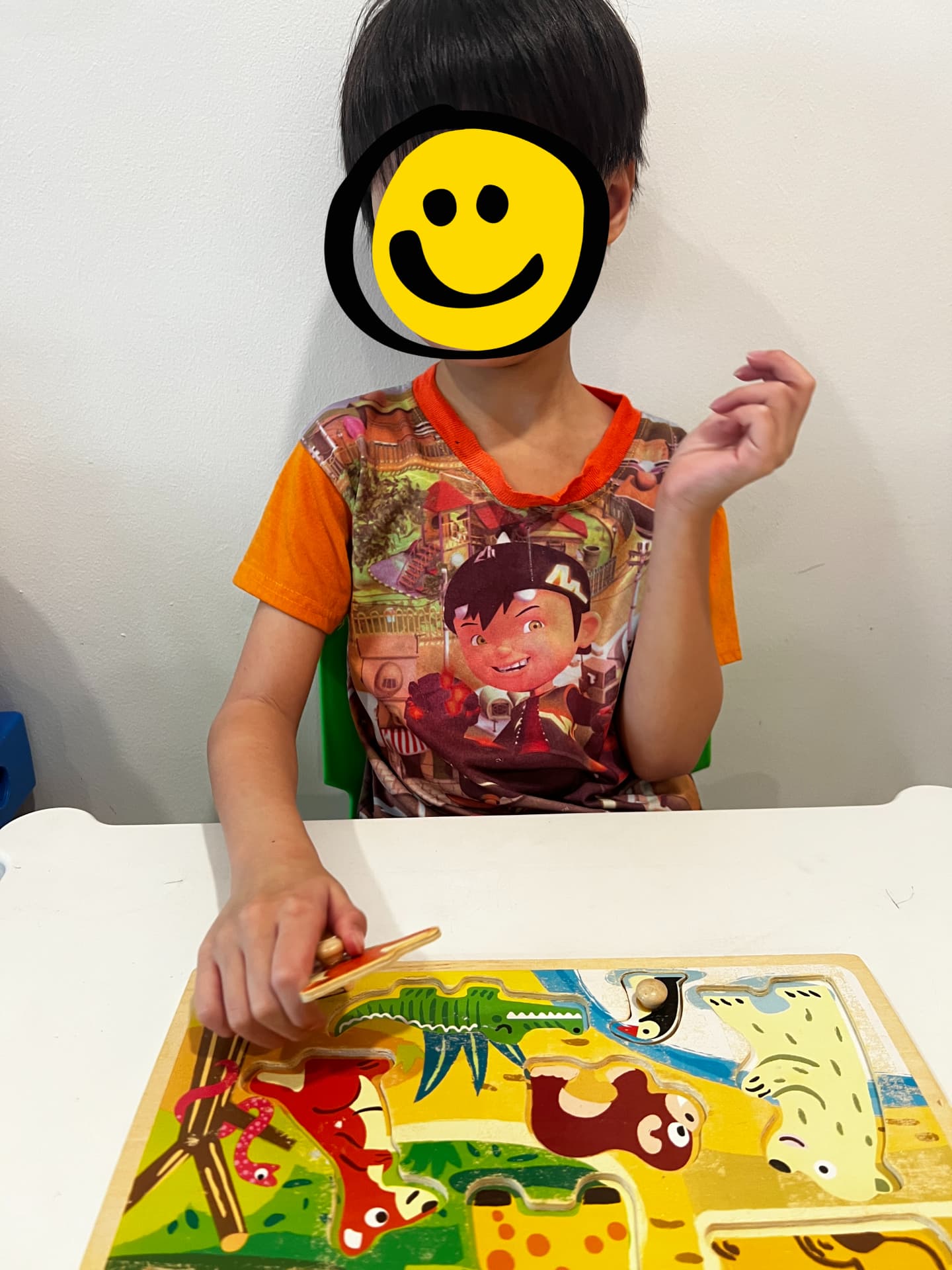 A child completing a wooden animal puzzle at a table.