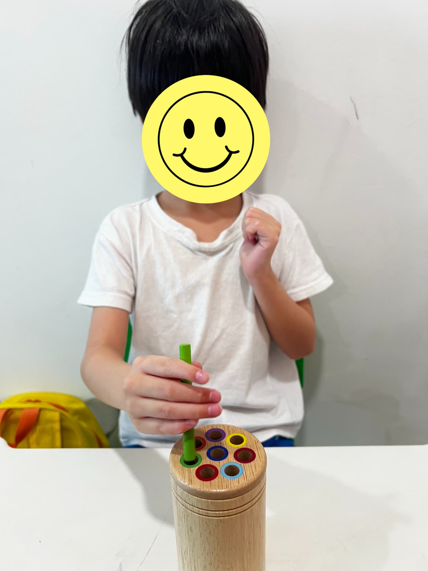 A child placing coloured pegs into a wooden peg toy.